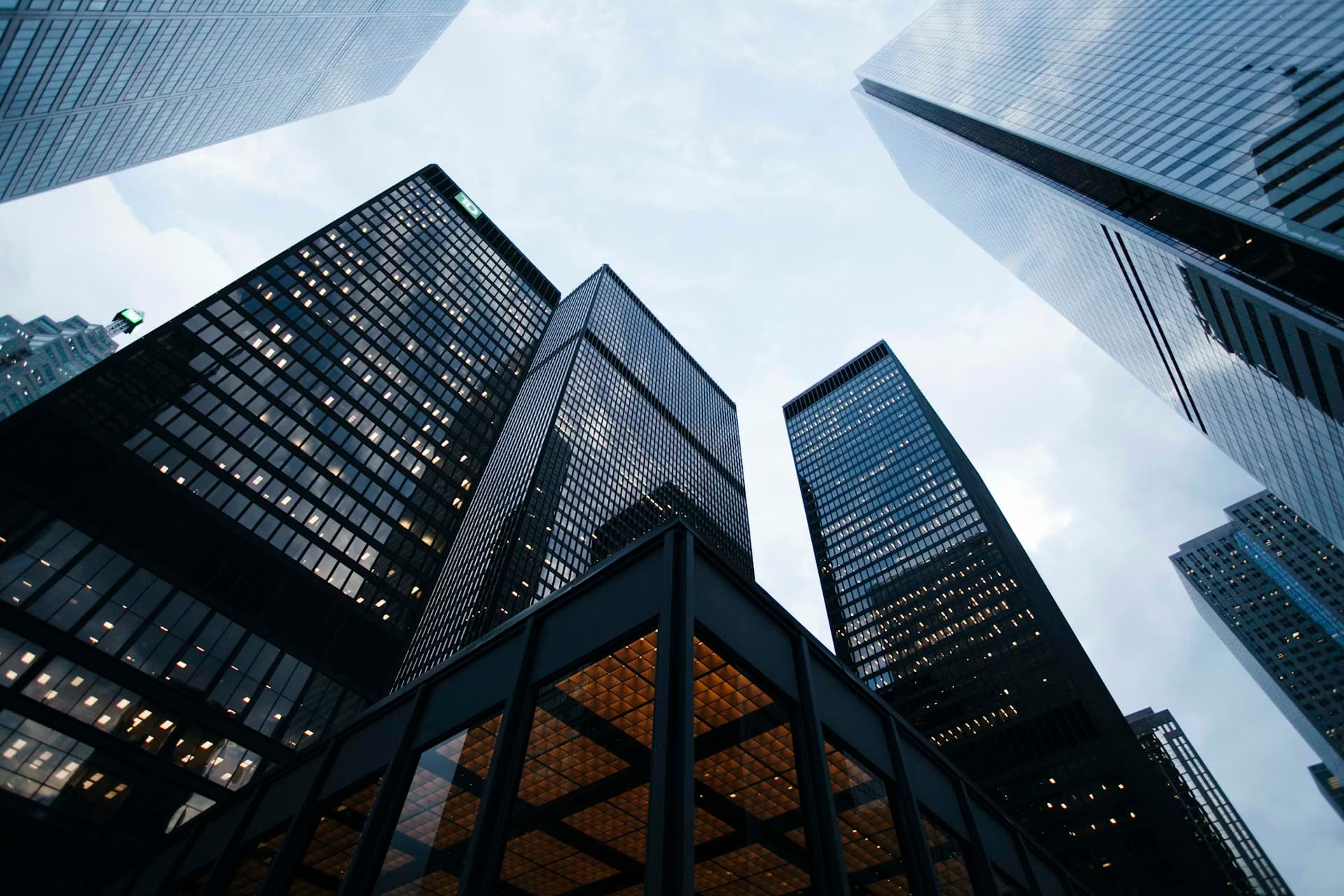 Modern glass skyscrapers viewed from below against a cloudy sky